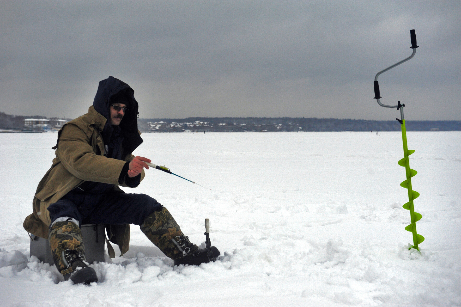 Рыбак ловит рыбу на замерзшем водохранилище в Подмосковье